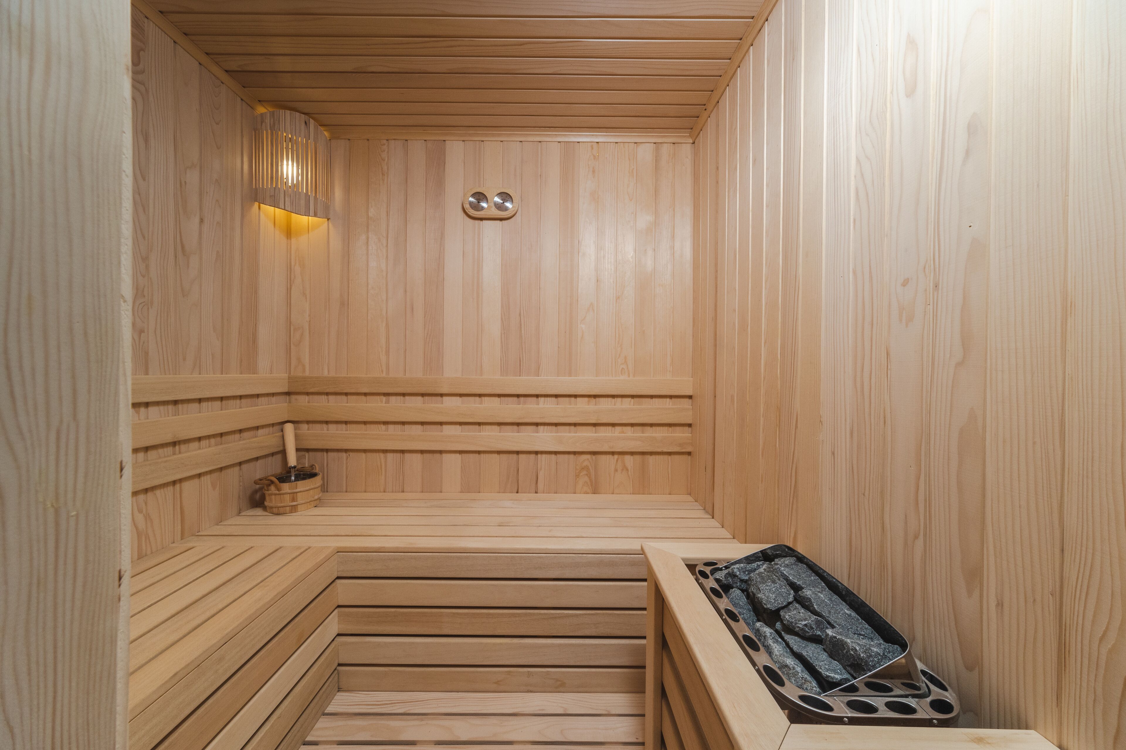 Una sauna de madera con bancos y una bandeja de piedra.