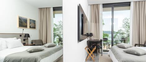 A hotel room with a bed, a desk, and a large window with curtains.
