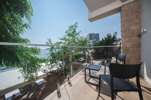 Un balcón con vistas al mar, mobiliario exterior y una pared de piedra.