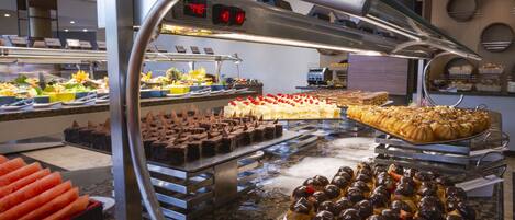 Un bufé con diversos postres y pastelería, incluyendo tartaletas de chocolate y profiteroles.
