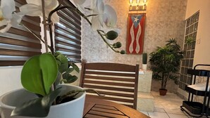 A dining area with a wooden table, potted plants, and a wall with a decorative flag.