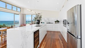 Una cocina moderna con una isla grande, armarios blancos y un refrigerador de acero inoxidable.