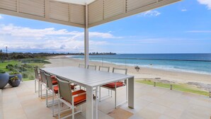 Un porche techado con una mesa y sillas con vista a la playa.