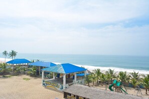 A beachside area with a covered seating area, a playground, and a view of the ocean. - ATICAN BEACH HOTEL AND RESORT (Lekki)