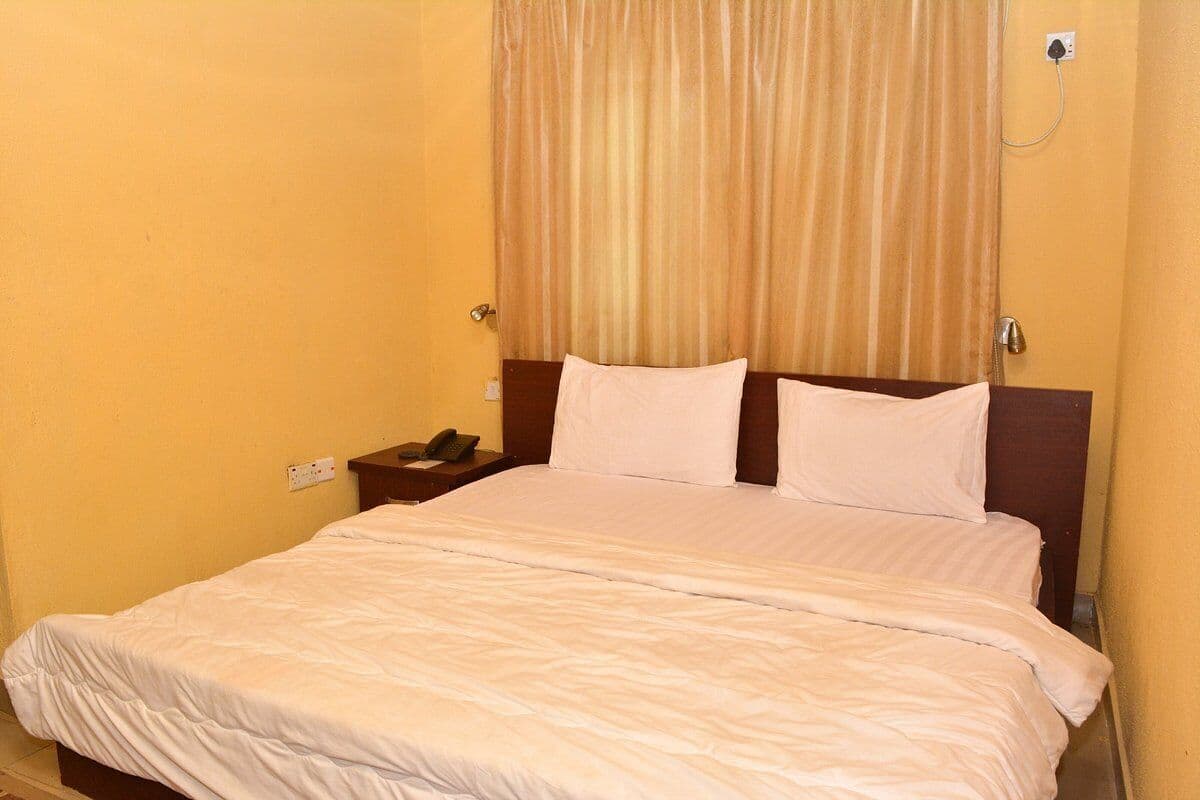 A single bed with white bedding in a room with yellow walls and a wooden headboard.