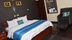 Ein Hotelzimmer mit einem Bett, einem Sessel, einem Nachttisch und einer Wand mit gerahmten Bildern.
