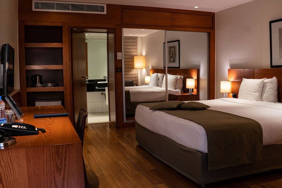 A hotel room with a large bed, bedside tables, a desk with a telephone, and a mirror.