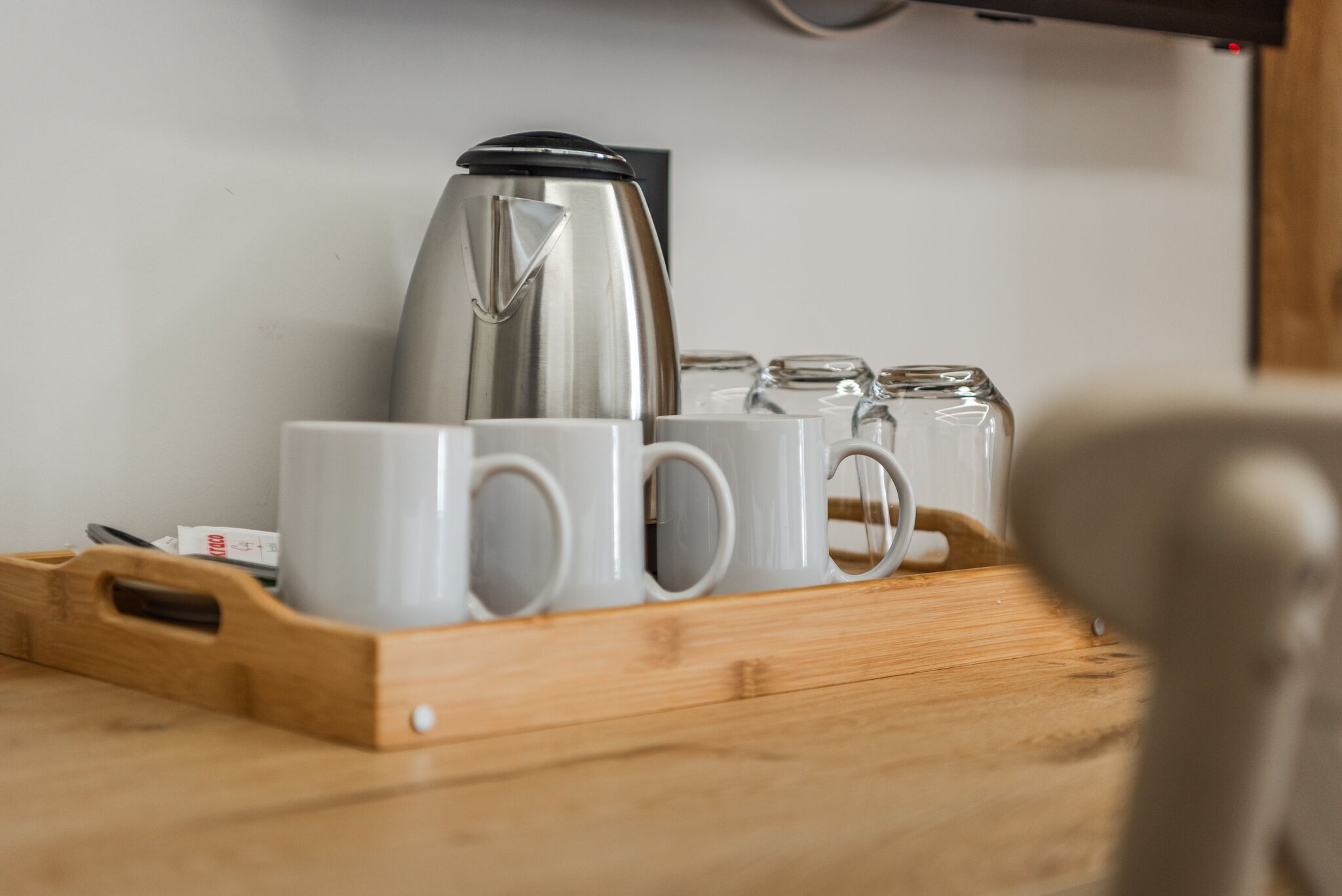 A tray with a coffee maker and several white mugs on a wooden surface.