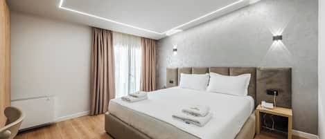 A modern hotel room with a large bed, bedside table, and a wall-mounted light fixture.
