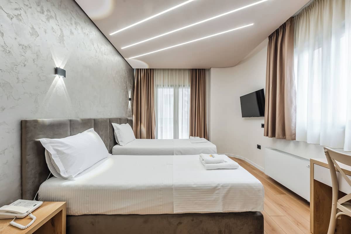 A hotel room with two beds, a flat-screen TV, a desk, and a telephone.