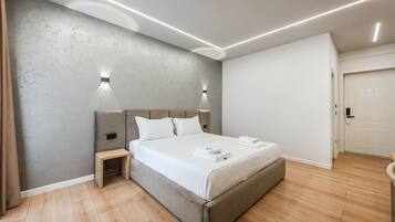 Un dormitorio moderno con una cama, lámparas de noche, una mesita de noche y suelo de madera.