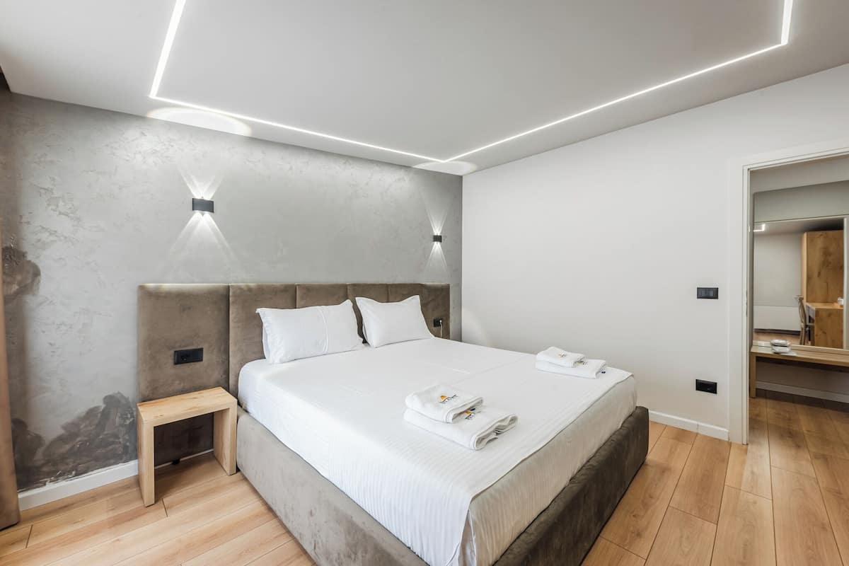 A modern bedroom with a large bed, bedside tables, and a built-in wardrobe.