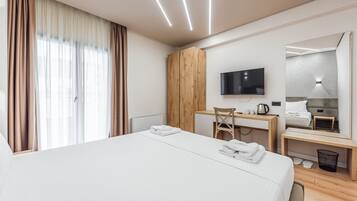 Una habitación de hotel moderna con una cama grande, un escritorio, una silla, un televisor y un espejo.