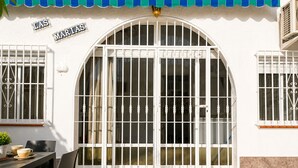 A building with a large arched entrance, a tiled patio, and a table with chairs. - Charming House with Nature (El Chaparral)