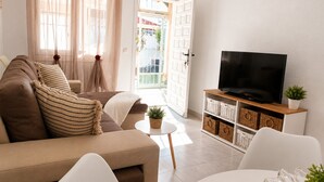 Un soggiorno con un divano, una televisione su un mobile in legno e un tavolino con una pianta.