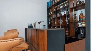 A bar area with leather chairs and a wooden shelf displaying various bottles. - 3H VILLAS HOTEL & LUXURY SHORT-LET  (Lekki)
