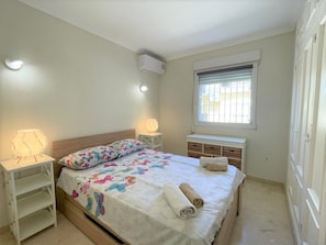 A bedroom with a bed, bedside lamps, a window with blinds, and a wall-mounted air conditioner. - T-0322, Mariposa, Modern villa in Dènia (Dénia)