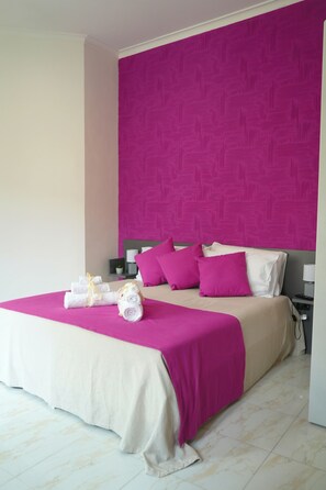 A hotel room with a large bed, a headboard, and a nightstand with a lamp.