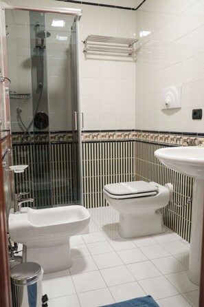 A bathroom with a glass-enclosed shower, a toilet, a bidet, and a sink.