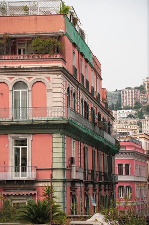 A multi-story building with balconies, arched windows, and a green awning.