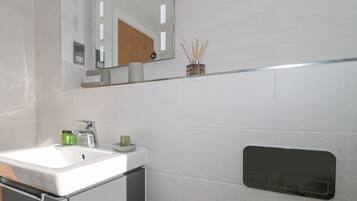 A modern bathroom with a white sink, mirror, and a towel rack.