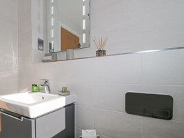 A modern bathroom with a white sink, mirror, and a towel rack.