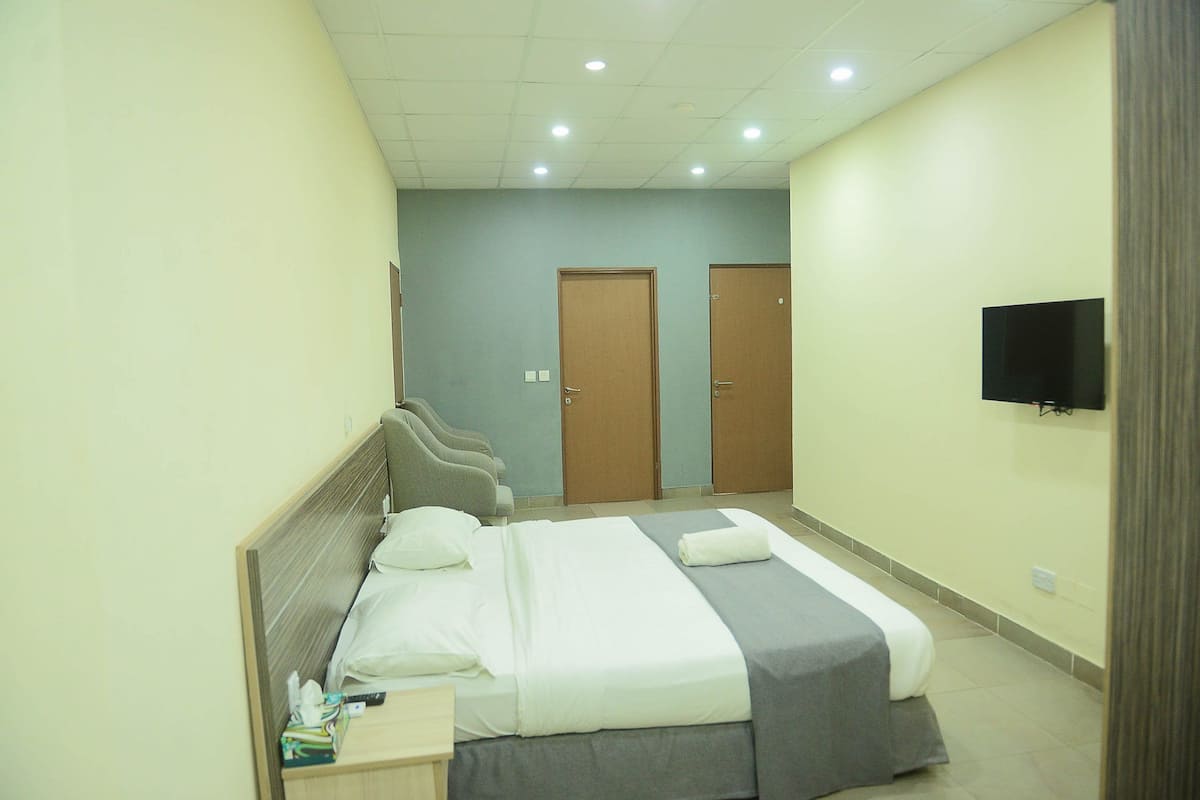 A hotel room with a bed, bedside table, and a television mounted on the wall.