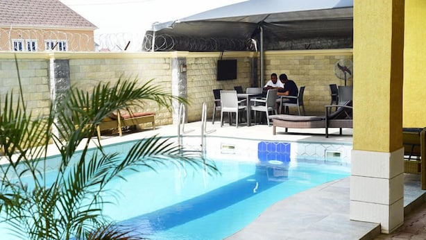 Piscina al aire libre con sillones de descanso y un área de estar techada.