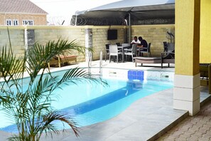 An outdoor swimming pool with lounge chairs and a covered seating area. - CATE HOUSE AND APARTMENT (Lagos)