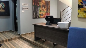 Un mostrador de recepción con una computadora, un teléfono y un cartel que indica recepción.