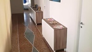 A hallway with a patterned carpet, a reception desk, and a door with a picture on the wall. - settimo sole affittacamere (Taranto)