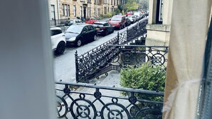 A street view with parked cars and a building with a balcony. - Beautiful one bed Apartment in Glasgow West End (Glasgow)
