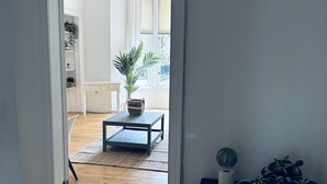 A hallway leading to a living room with a wooden floor, a coffee table, and a potted plant. - Beautiful one bed Apartment in Glasgow West End (Glasgow)