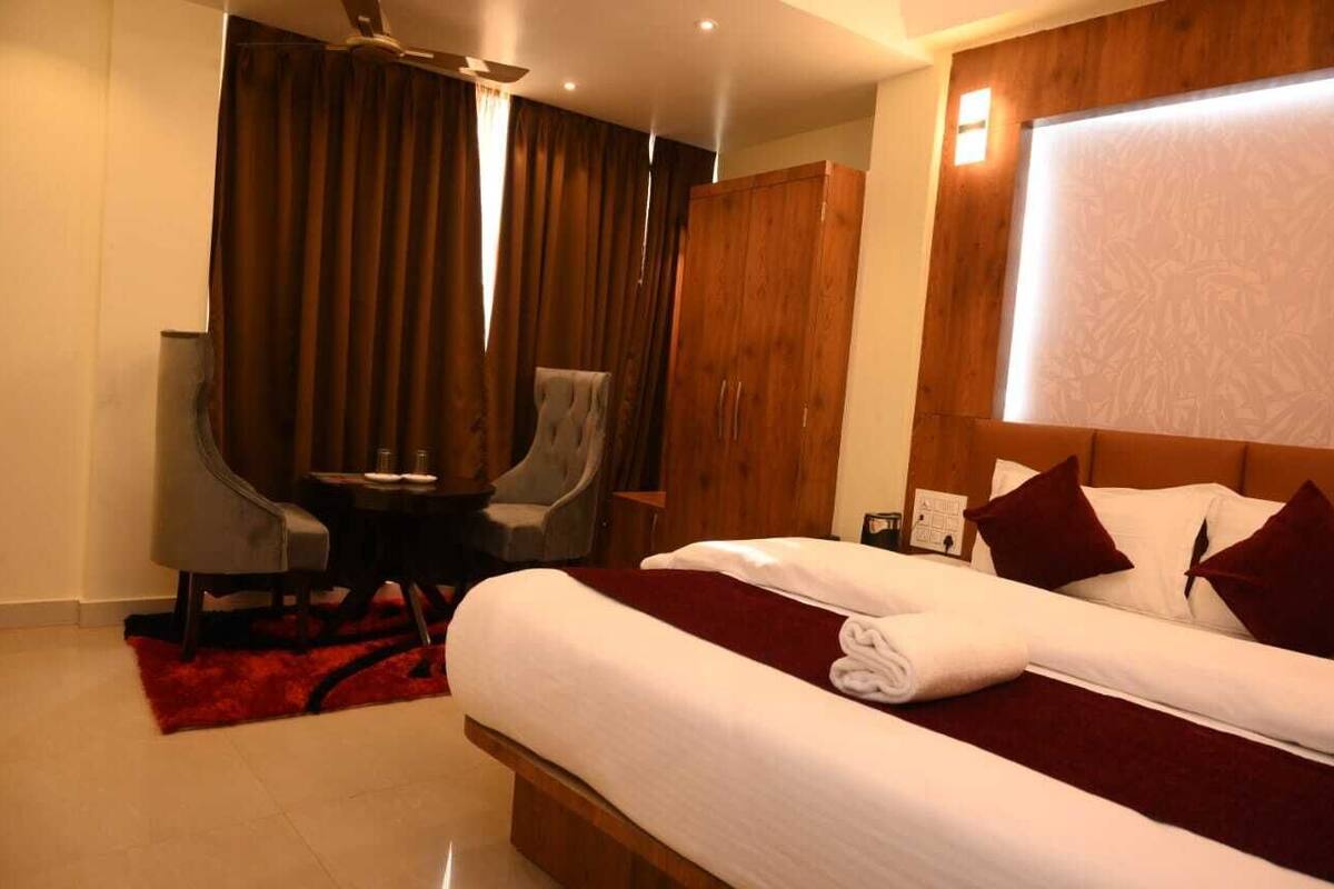 A hotel room with a large bed, a desk, a chair, and a wardrobe.