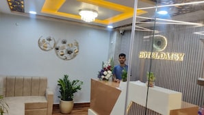 A reception area with a modern design, including a reception desk, a sofa, and decorative wall art. - Hotel Daisy (Guwahati)