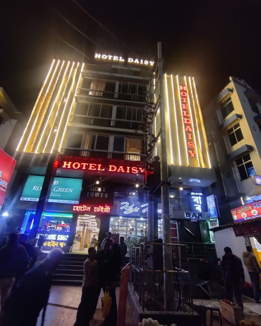 Un hotel con un llamativo letrero 'HOTEL DAISY', varios pisos y una zona de bar con señalización visible.
