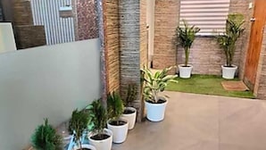 A courtyard with potted plants, a small lawn, and a brick wall. - Hotel Daisy (Guwahati)