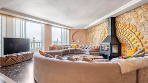 A spacious living room with a large sectional sofa, a flat-screen TV, and a stone-patterned wall.