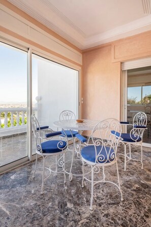A balcony with a round table and four chairs, a white ceiling, and a view of the sea. - Haddad's luxurious villa with an amazing view and swimming pool (Tangier)