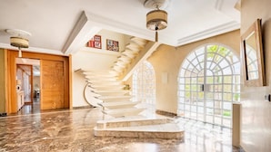 A grand staircase with a marble finish, leading to a balcony with large arched windows.