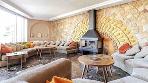 A modern living room with a stone wall, a fireplace, and a sofa set.