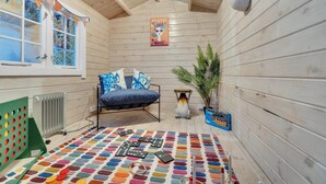 Une pièce chaleureuse avec un décor intérieur en bois, un lit avec une literie bleue, un radiateur, un tapis coloré et une affiche accrochée au mur.