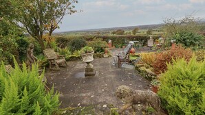 A garden patio with stone flooring, outdoor furniture, and a statue of a lion. - The Barn (Morpeth)