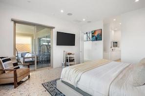 Une chambre à coucher moderne avec un lit, une chaise, un bureau et un téléviseur fixé au mur.