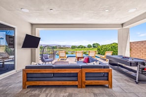 An outdoor living area with a pool, lounge chairs, a sofa, and a pool table. - Desert Oasis Retreat | EV Charger, GolfCourseViews (La Quinta)