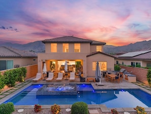 Une maison à deux étages avec une piscine, du mobilier d’extérieur et un espace patio.