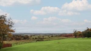 A grassy field with a fence, trees, and a distant view of hills. - High Shaftoe (Morpeth)