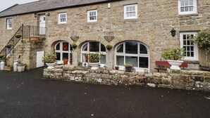 A stone building with multiple windows, a staircase, and potted plants. - High Shaftoe (Morpeth)