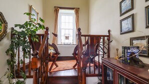 A wooden staircase with a view to a window, a bookshelf with books, and a potted plant. - High Shaftoe (Morpeth)