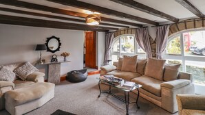 A cozy living room with a sofa, armchairs, a glass coffee table, and a fireplace. - High Shaftoe (Morpeth)